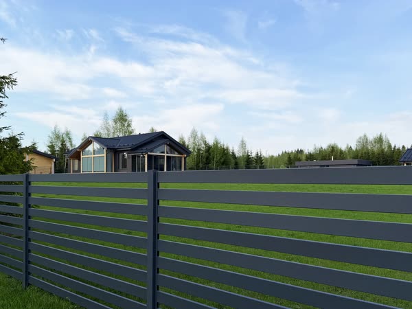 Участки и дома поселка за ограждением, вдали лес